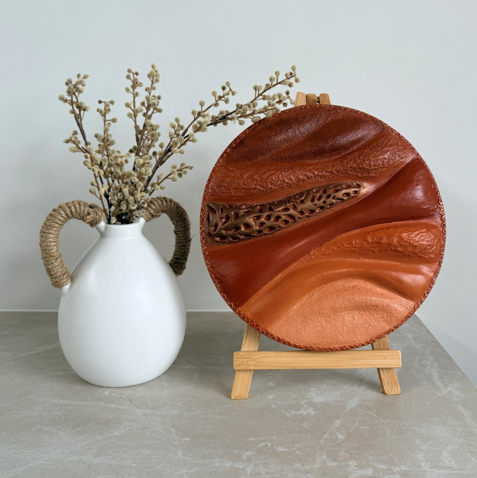 Round textured sculpture painting styled with white vase